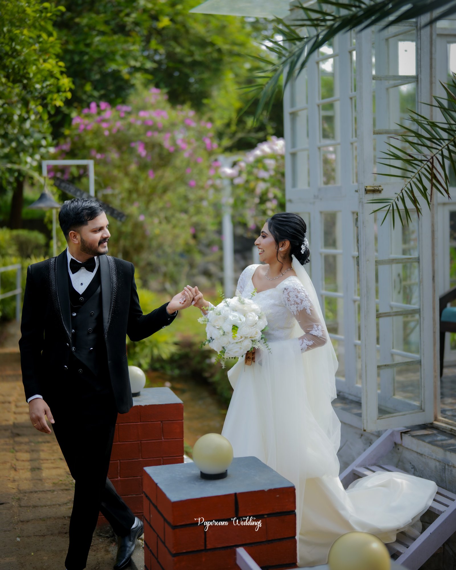 Newlyweds walking hand in hand through a garden