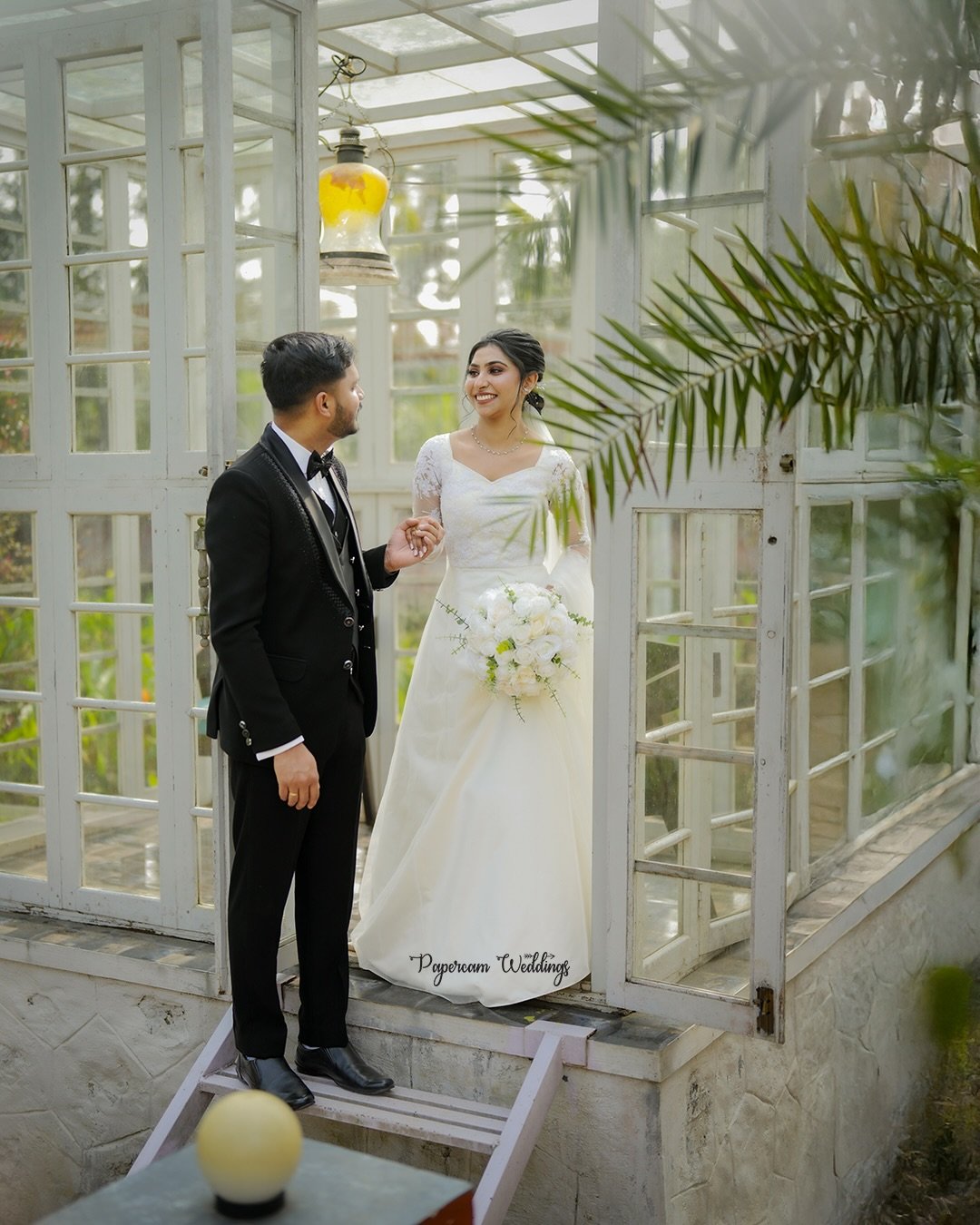 Newlyweds smiling together at a garden glasshouse